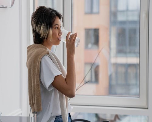 A person drinking a glass of water in modern apartment